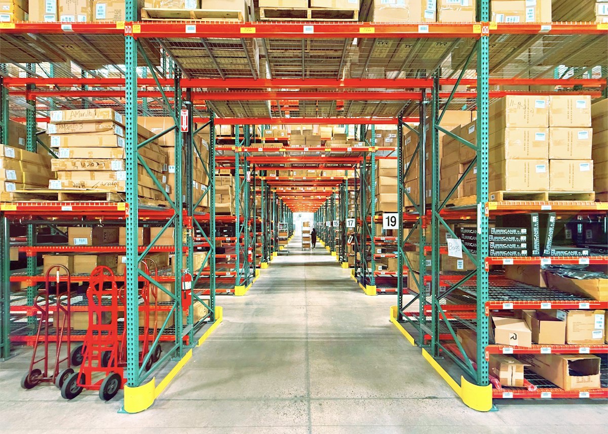 A warehouse aisle with tall racks of boxed stock